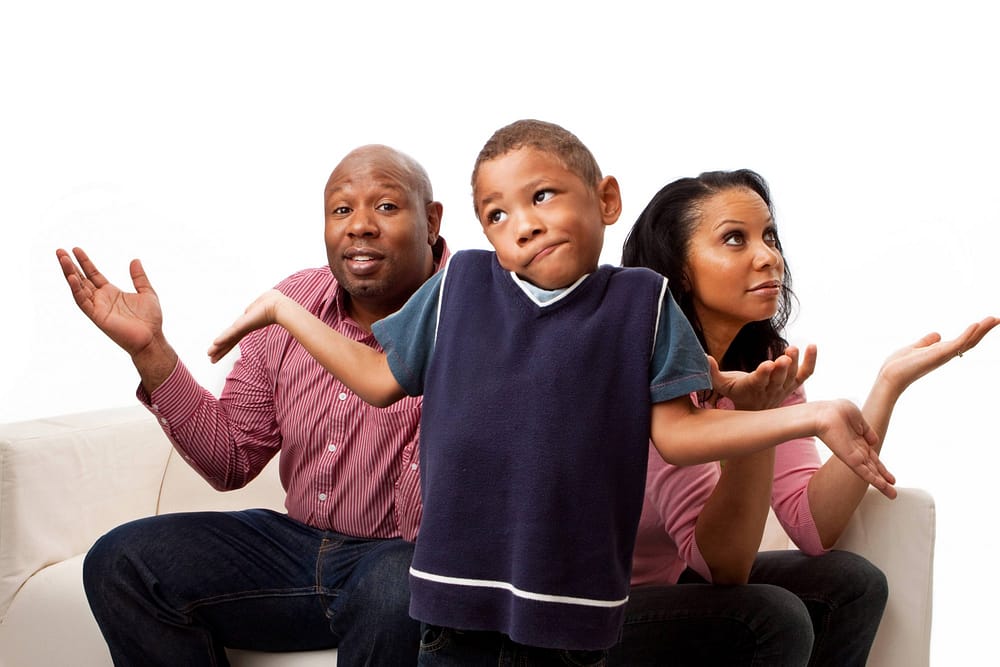 Black parents and boy gesturing with hands and faces that they are confused.