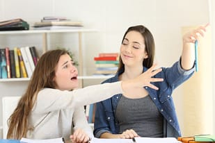 Teen girl anxiously reaching for her phone.