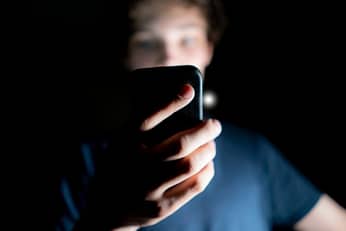 Teenage boy watching porn on his phone at night.