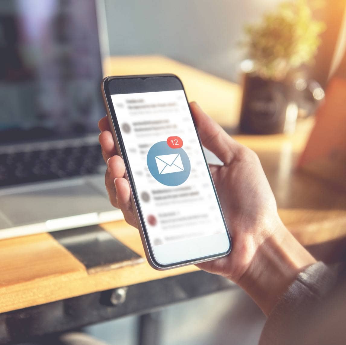 Hand holding a phone reading email.